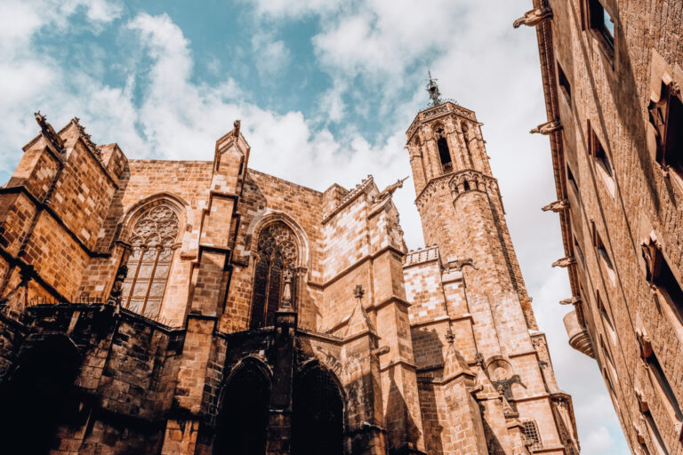 Rear view of the apse and bell tower of Barcelona Cathedral from Carrer de la Pietat, showing Gothic windows and gargoyles.