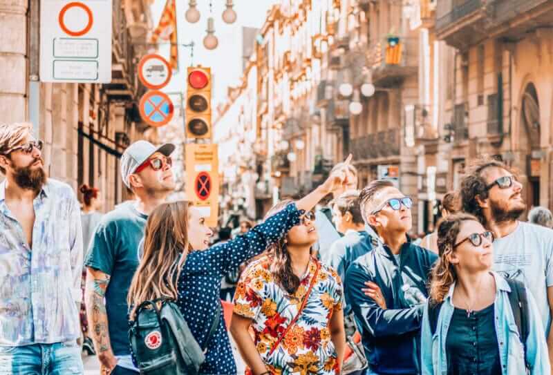 Jana leading a tour group in Plaça de Sant Jaume in Barcelona’s Gothic Quarter, with guests looking up at historic buildings.